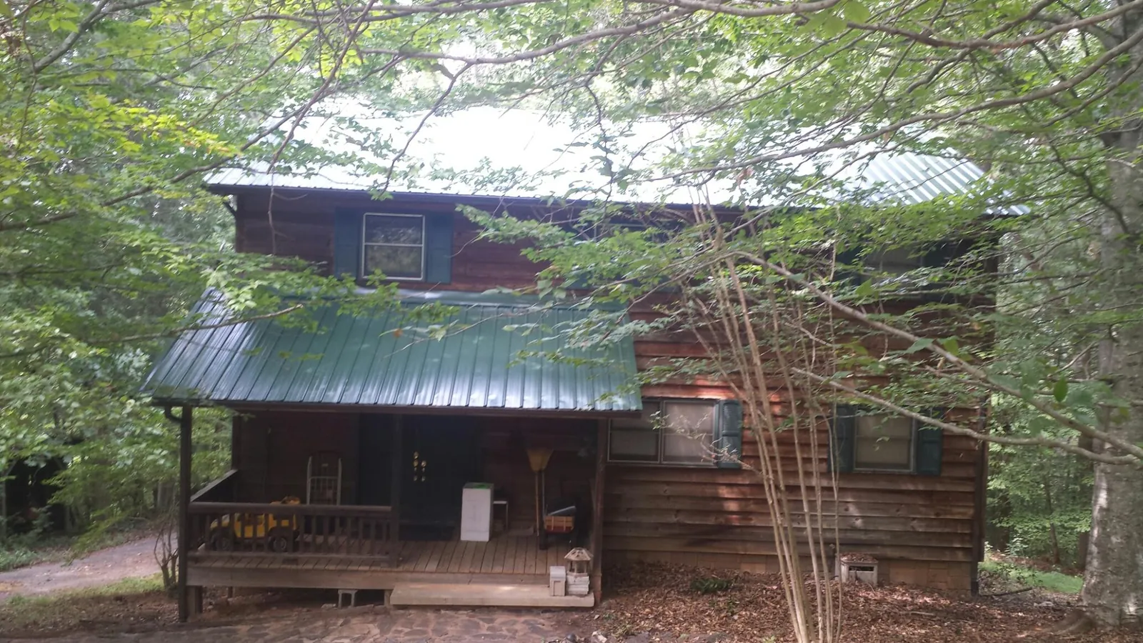 Green metal roof and covered porch on a log cabin in D Lo