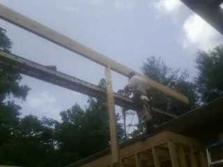 Carpenter setting a ridge beam over a new addition frame — Ice Dam Removal by Roofing Brothers in D Lo