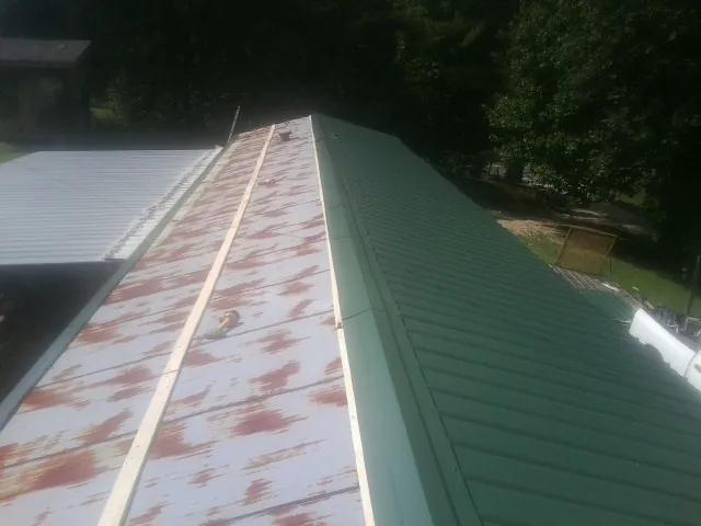 Old rusted panels beside newly installed green metal roofing — Wind Damage Roof Repair by Roofing Brothers in D Lo