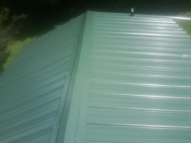 New green metal panels meeting at the ridge of a roof — Flat Roof Repair work by our crew in D Lo