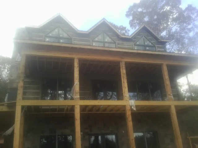 Dormers and porch framing on a large log home under construction — Roof Coating work by our crew in D Lo