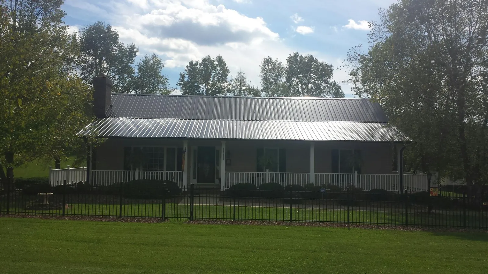Gray metal roof on a brick ranch with a full width front porch — Gutter Guard Installation work by our crew in D Lo